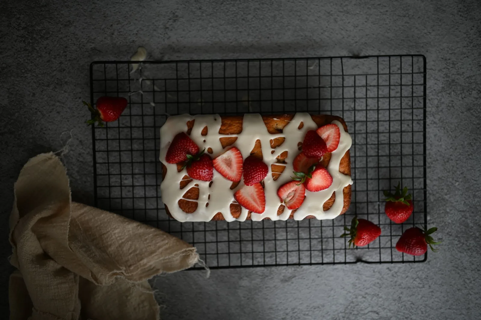 Cake covered with a white icing, resting on a rack