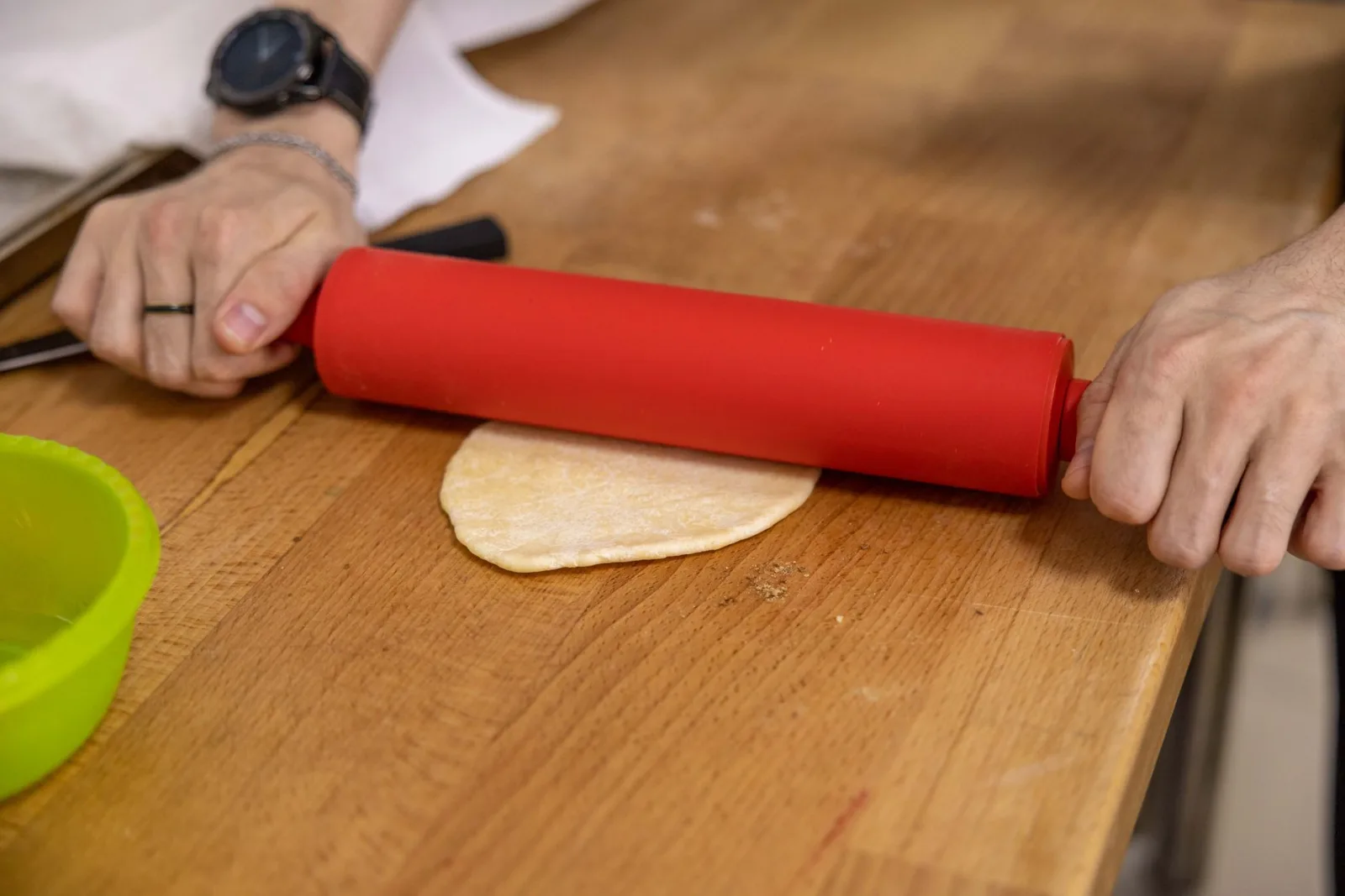 Hands rolling out pastry dough on a work surface